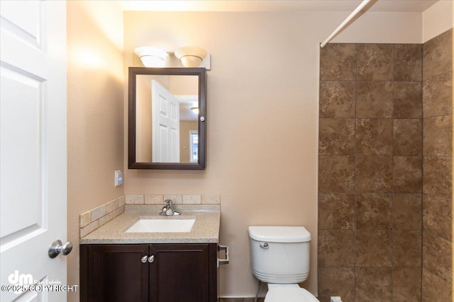 bathroom with vanity, tiled shower, and toilet