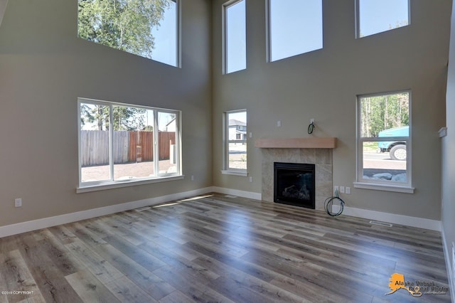 unfurnished living room featuring wood-type flooring and a tile fireplace