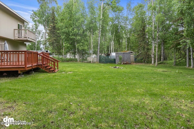 view of yard featuring a deck, an outbuilding, fence, and a balcony