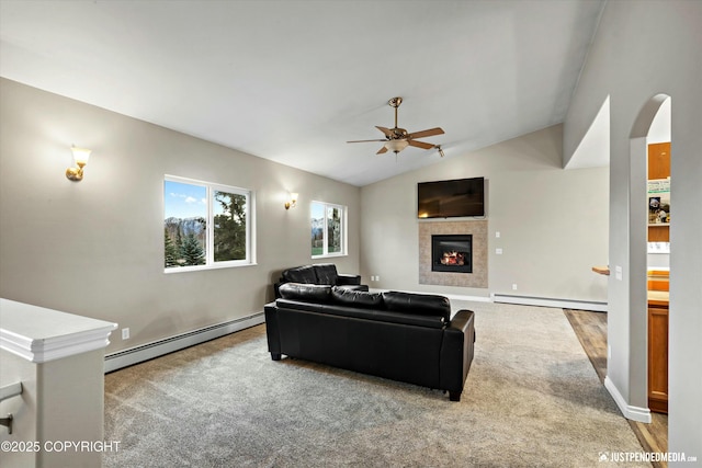 living area featuring lofted ceiling, a tiled fireplace, baseboard heating, and ceiling fan