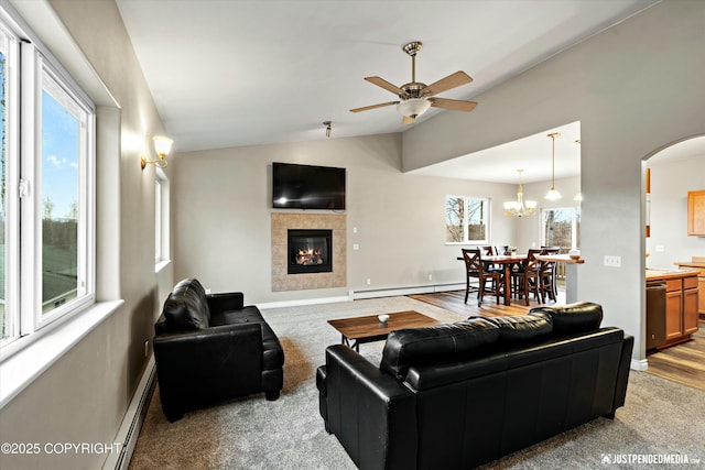 living room with arched walkways, a tiled fireplace, a baseboard radiator, vaulted ceiling, and carpet flooring