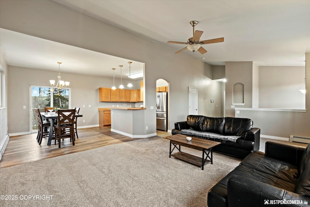 living area featuring a baseboard heating unit, light carpet, baseboards, and ceiling fan with notable chandelier