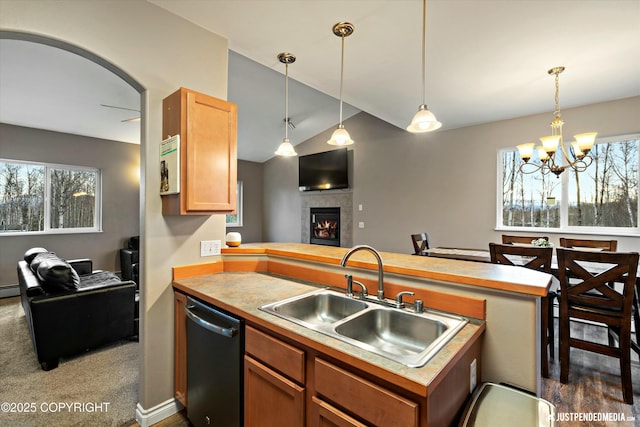 kitchen with a tiled fireplace, open floor plan, a peninsula, stainless steel dishwasher, and a sink