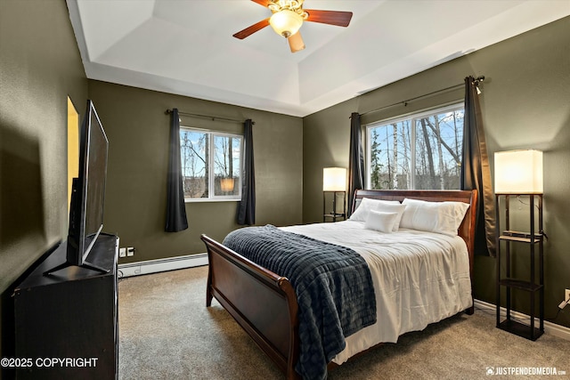 bedroom with a baseboard radiator, carpet floors, a ceiling fan, baseboards, and a tray ceiling