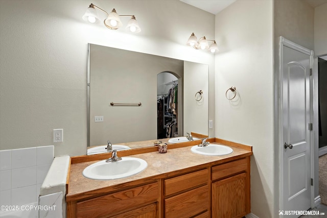 bathroom with double vanity, a walk in closet, and a sink