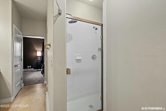 bathroom with a shower stall, a baseboard heating unit, baseboard heating, and baseboards