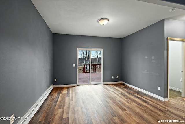 spare room featuring baseboards, baseboard heating, and wood finished floors