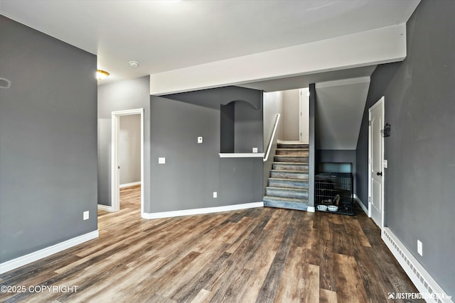 unfurnished living room featuring stairway, baseboards, a baseboard heating unit, and wood finished floors