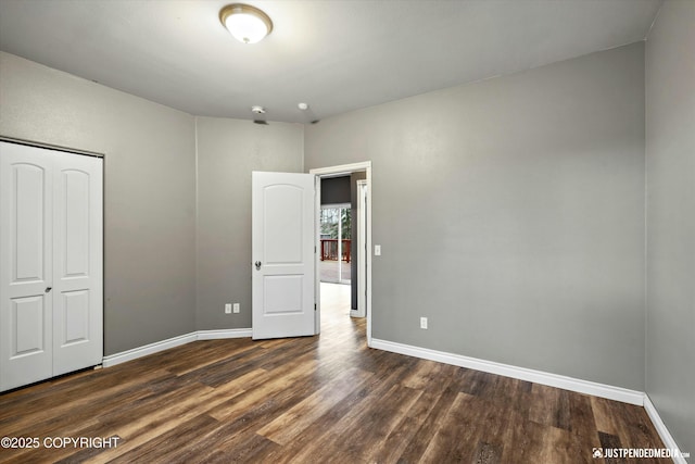 unfurnished bedroom with a closet, baseboards, and dark wood-type flooring