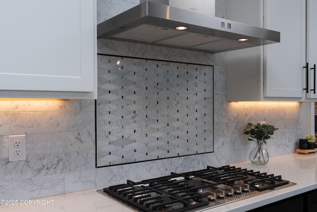 kitchen featuring stainless steel gas stovetop, exhaust hood, white cabinets, and decorative backsplash