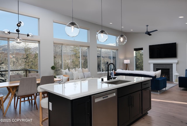 kitchen featuring sink, decorative light fixtures, a kitchen island with sink, dishwasher, and light hardwood / wood-style floors