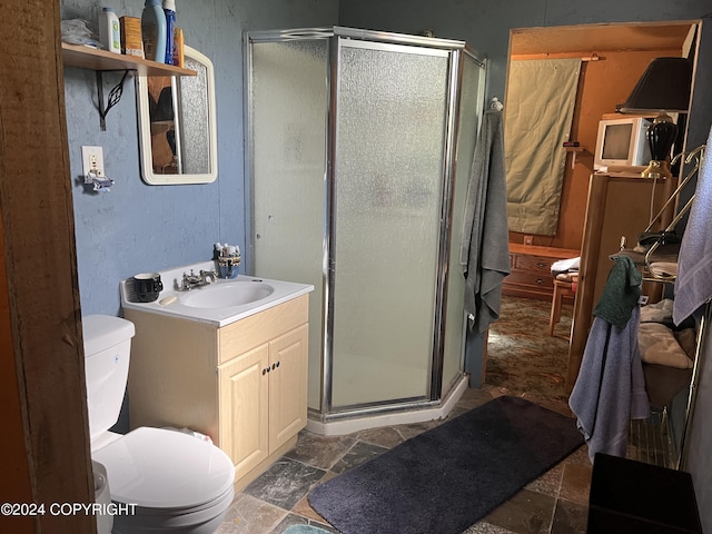 bathroom with vanity, a shower with door, and toilet