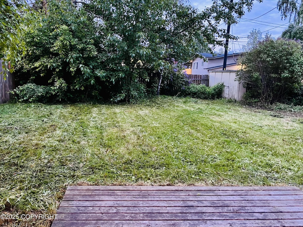 view of yard featuring a wooden deck and a storage unit