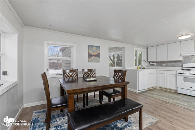 dining room with ornamental molding, sink, and light wood-type flooring