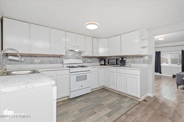 kitchen featuring white cabinetry, sink, backsplash, gas range gas stove, and light hardwood / wood-style flooring