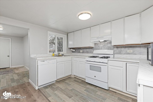 kitchen with tasteful backsplash, sink, white cabinets, white appliances, and light hardwood / wood-style flooring