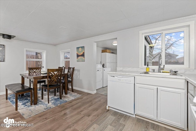 dining area with independent washer and dryer, a healthy amount of sunlight, light hardwood / wood-style floors, and sink