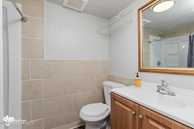 bathroom featuring vanity, toilet, tile walls, and walk in shower