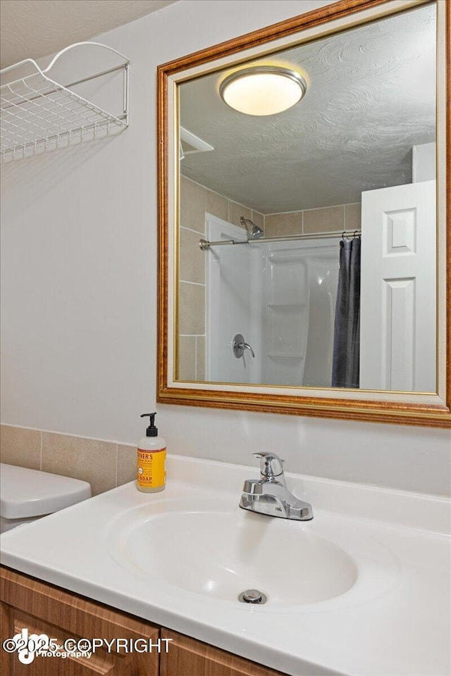 bathroom featuring vanity, curtained shower, a textured ceiling, and toilet