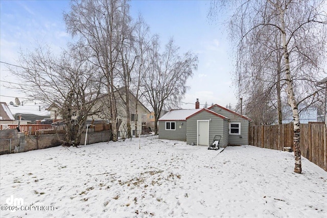 snow covered back of property featuring an outdoor structure