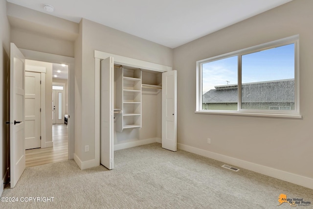 unfurnished bedroom featuring a closet and light carpet