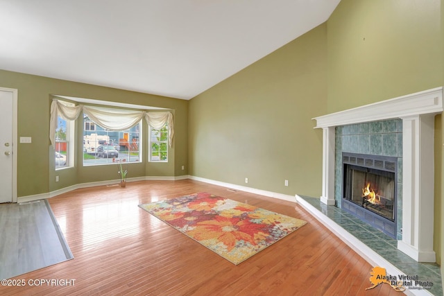 7541 Florence Cir, Anchorage, AK 99507 - unfurnished living room featuring a tile fireplace, wood finished floors, lofted ceiling, and baseboards