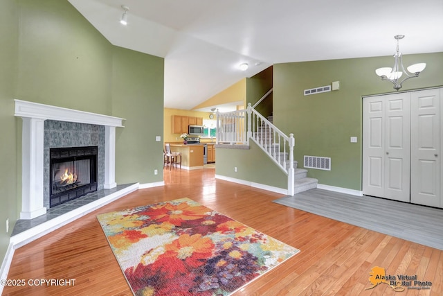7541 Florence Cir, Anchorage, AK 99507 - foyer with lofted ceiling, light wood finished floors, stairs, a tiled fireplace, and baseboards