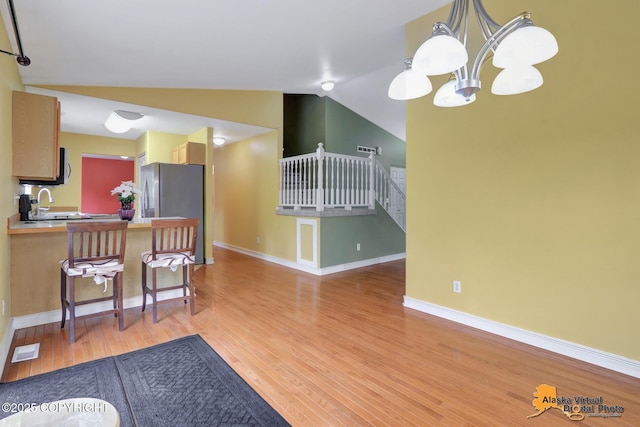 7541 Florence Cir, Anchorage, AK 99507 - kitchen with light wood finished floors, vaulted ceiling, a chandelier, baseboards, and freestanding refrigerator