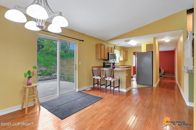 7541 Florence Cir, Anchorage, AK 99507 - kitchen featuring stainless steel appliances, a peninsula, light wood finished floors, a chandelier, and a breakfast bar area