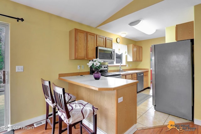 7541 Florence Cir, Anchorage, AK 99507 - kitchen featuring stainless steel appliances, a peninsula, a sink, light countertops, and a breakfast bar area