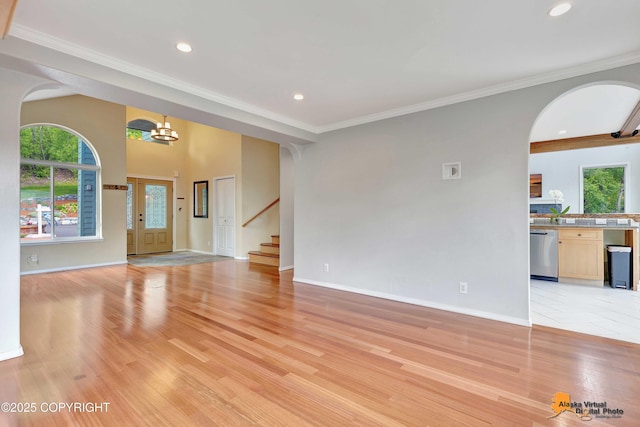 10235 Stewart Dr, Eagle River, AK 99577 - unfurnished living room with arched walkways, light wood finished floors, healthy amount of natural light, recessed lighting, and crown molding