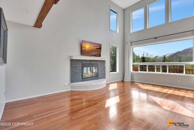 10235 Stewart Dr, Eagle River, AK 99577 - unfurnished living room featuring a towering ceiling, a fireplace, wood finished floors, and beamed ceiling