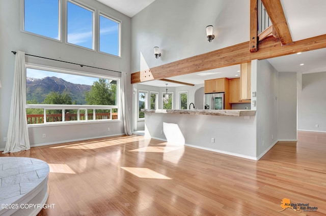 10235 Stewart Dr, Eagle River, AK 99577 - unfurnished living room with a high ceiling, light wood finished floors, beamed ceiling, and recessed lighting