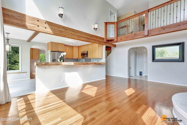 10235 Stewart Dr, Eagle River, AK 99577 - unfurnished living room with arched walkways, a towering ceiling, light wood-style floors, and beam ceiling