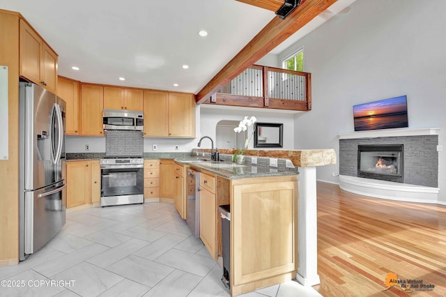 10235 Stewart Dr, Eagle River, AK 99577 - kitchen with stainless steel appliances, light brown cabinets, a peninsula, light stone counters, and a fireplace