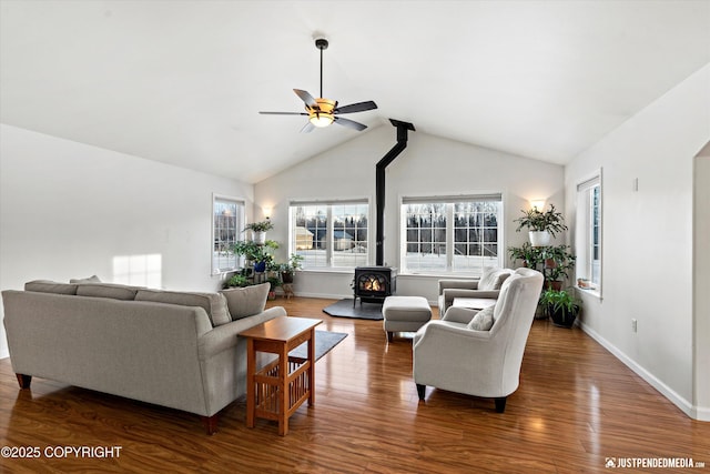 living room with lofted ceiling, dark wood-type flooring, ceiling fan, and a wood stove