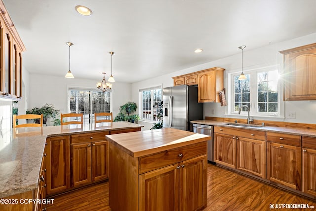 kitchen featuring sink, decorative light fixtures, stainless steel appliances, and a center island