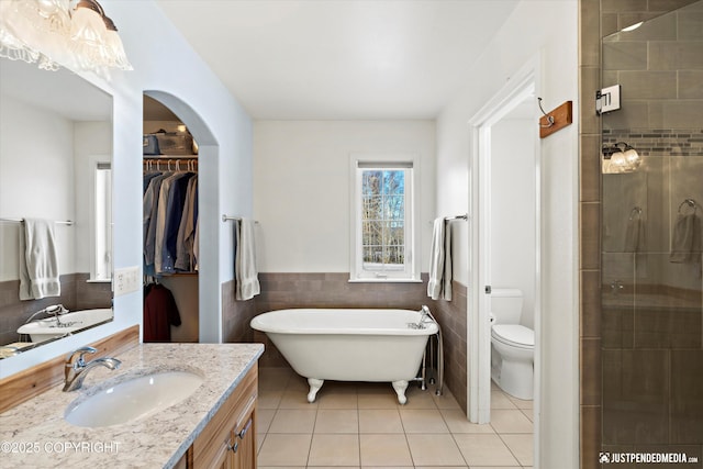 full bathroom with toilet, separate shower and tub, tile walls, vanity, and tile patterned flooring