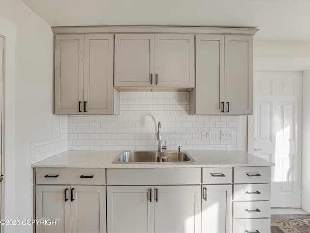 kitchen featuring light stone counters, sink, and decorative backsplash