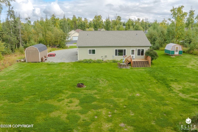 rear view of house featuring a shed, a wooden deck, and a yard