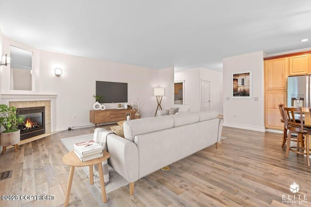 living room featuring a tile fireplace and light hardwood / wood-style flooring