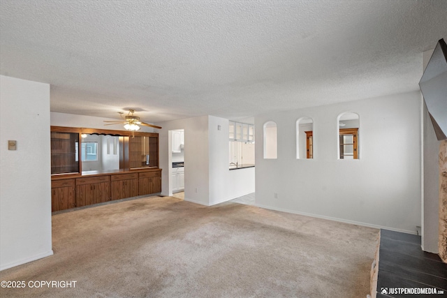 unfurnished living room featuring carpet floors, a textured ceiling, and ceiling fan