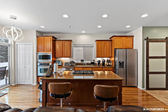 kitchen with a center island, sink, a barn door, and appliances with stainless steel finishes