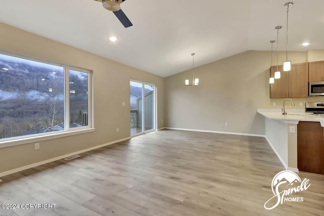 unfurnished living room with lofted ceiling, sink, ceiling fan with notable chandelier, and light wood-type flooring