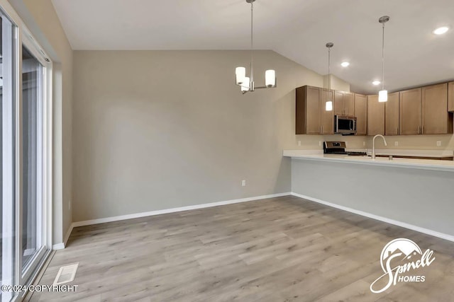 kitchen with lofted ceiling, sink, hanging light fixtures, light hardwood / wood-style flooring, and stainless steel appliances