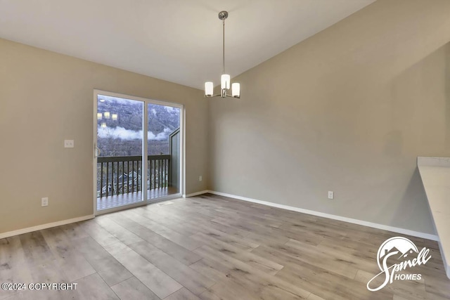 unfurnished dining area featuring hardwood / wood-style flooring, lofted ceiling, and a chandelier