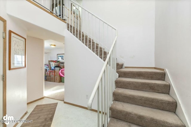 stairway featuring a towering ceiling and carpet