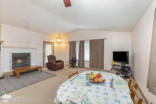 carpeted bedroom with a tiled fireplace, vaulted ceiling, and ceiling fan