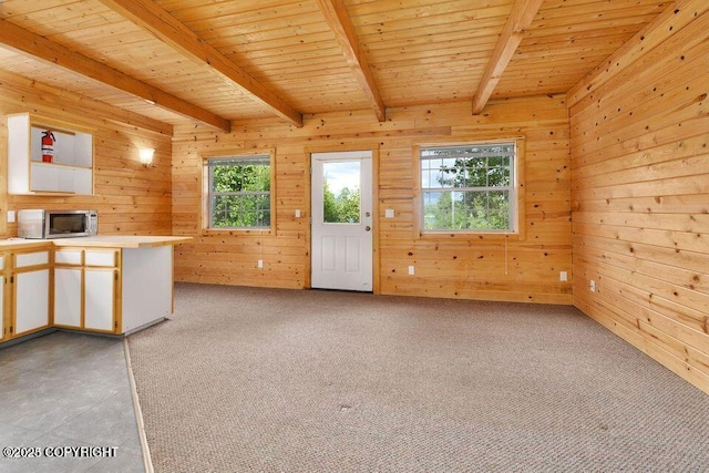 interior space with wooden walls, beam ceiling, light carpet, and wooden ceiling