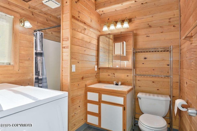 bathroom featuring wood walls, washer / clothes dryer, walk in shower, vanity, and toilet